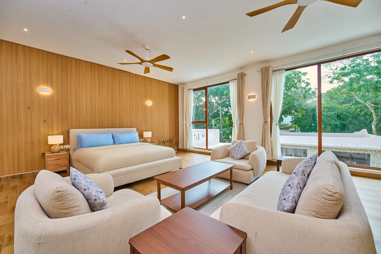A spacious king bedroom with a private sitting area and garden outlook
